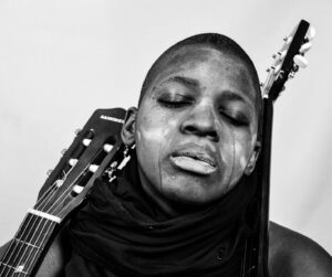 Close-up black and white portrait of a person reflecting deep emotion with a guitar.