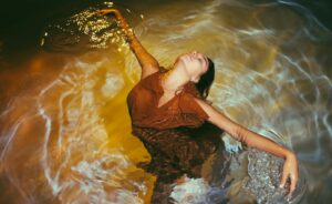 A woman gracefully moves in water, creating captivating ripples and reflections.