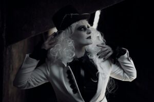 A striking gothic fashion portrait, featuring dark, dramatic makeup and attire in a moody setting.